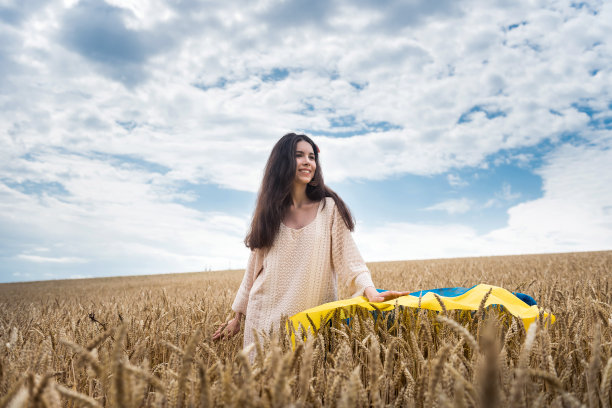 举着乌克兰国旗的女孩走过一片成熟的麦田图片下载