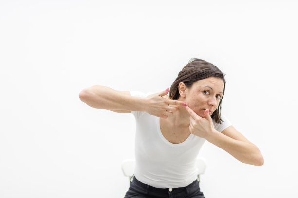 有痤疮问题的妇女在室内挤痘痘的照片。图片下载