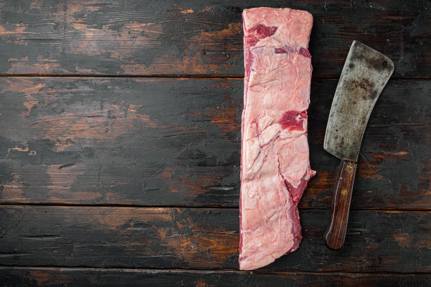 短肋骨骨在炖肉，和老屠夫菜刀，在旧的深色木桌背景，顶部视图平躺，与文本复制空间图片下载