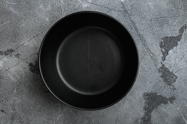 黑色的碗，带有文本或食物的复制空间，带有文本或食物的复制空间，顶视图平铺，放在灰色的石头桌子背景上图片下载