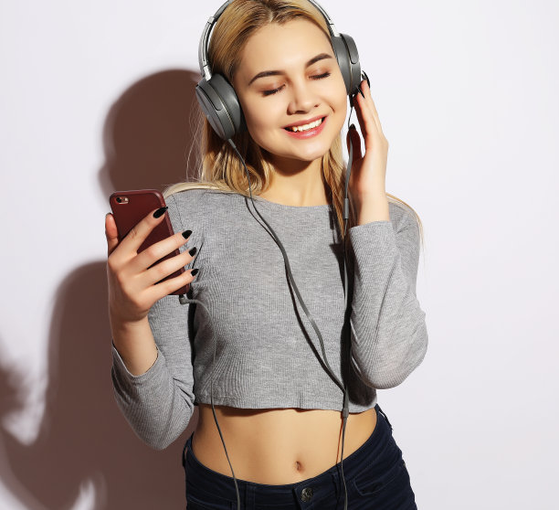 快乐的年轻女人用智能手机听音乐图片下载