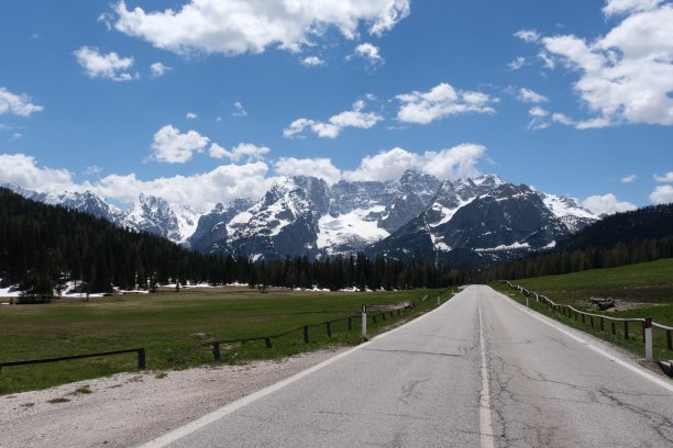 从一辆电动汽车的挡风玻璃上拍摄的画面，前面是白雪覆盖的阿尔卑斯山脉。阳光明媚的春天。在山路上拍摄的第一人称视角。没有人。图片下载