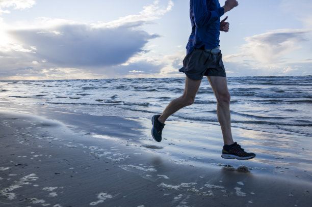一个慢跑者为了跑马拉松，在清晨跑过海滩图片下载