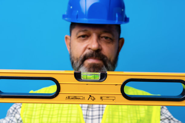 男勤杂工的肖像在蓝色的背景下拿着建筑水平图片下载