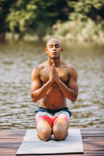 冥想。温暖的夏日里，英俊专注的男人在码头上冥想图片下载