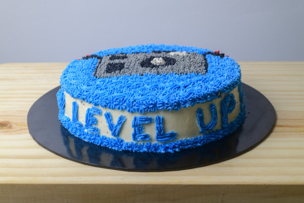 从高角度拍摄生日蛋糕。用蓝色字母写的"Level up"在木桌上准备切的自制蛋糕。图片下载