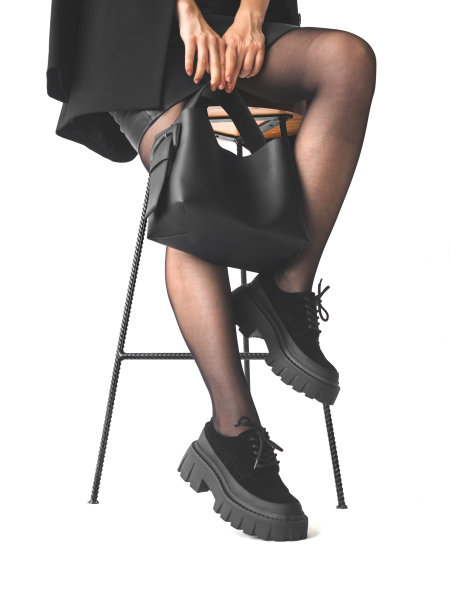 女人握着黑色皮革手袋而坐在椅子上，孤立在白色背景，购物和商人的概念照片图片下载