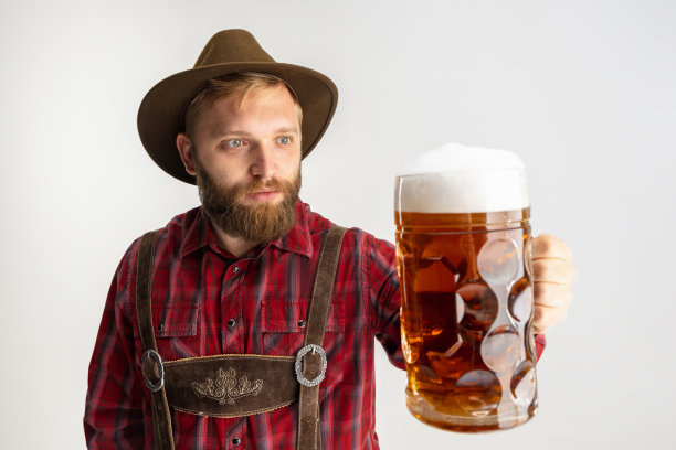 半身像，留着胡须的男子戴着帽子，穿着传统的巴伐利亚服装，手里拿着一个巨大的杯子，杯子里盛着浅泡沫啤酒，在白色的背景下分开。摩天观景轮图片下载