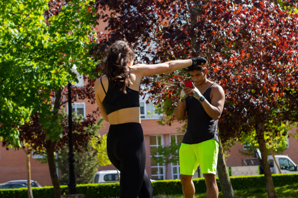 一名年轻女孩在户外公园练习拳击，她的拉丁教练拍摄了她的视频图片下载
