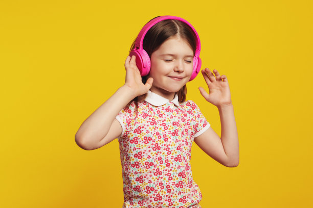 戴着粉色耳机的快乐孩子，闭着眼睛听着音乐跳舞图片下载