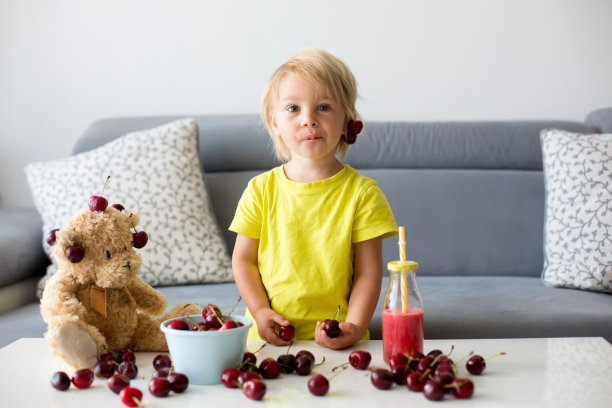 金发幼童，可爱男孩，和泰迪熊一起吃樱桃图片下载