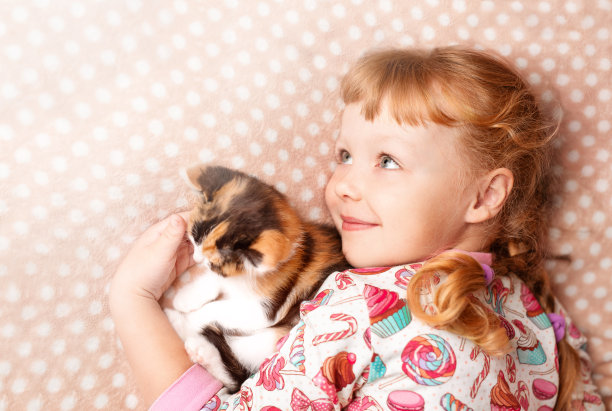 一个金发小女孩和一只斑点猫玩耍图片下载
