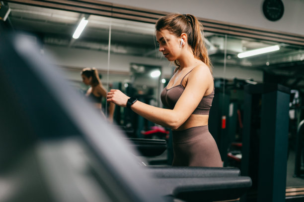 一名年轻女子在跑步机上跑步的全长侧面照片图片下载
