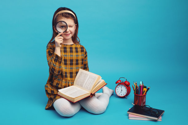 可爱的小女生，穿着格子裙，拿着放大镜，微笑着图片下载