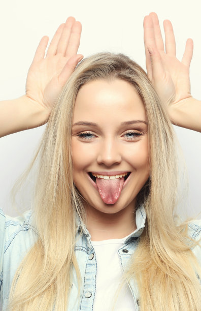 一个年轻美丽的女孩的肖像在白色的背景与一个微笑显示喇叭在相机图片下载