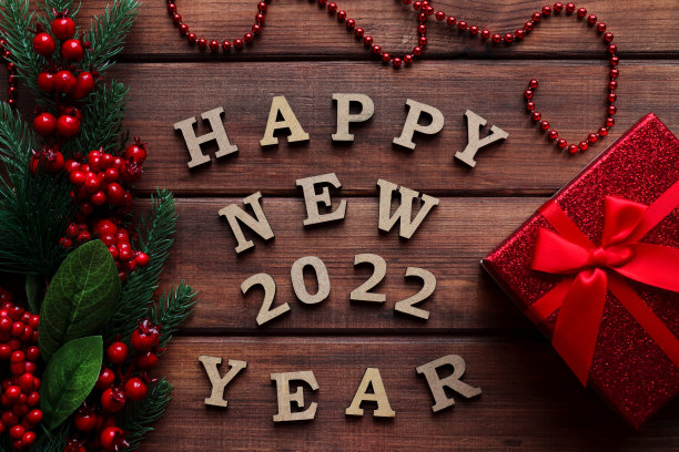 木桌上放着云杉树枝、红色浆果和礼盒，上面写着“新的2022年快乐”的新年贺卡。俯视图，平躺图片下载