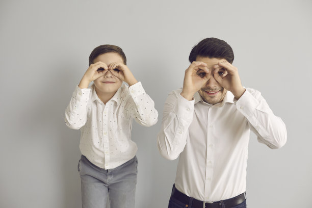 高兴的父亲和小儿子看着他们的手做的假想的双筒望远镜。图片下载