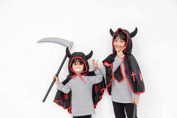 万圣节派对上快乐的兄弟姐妹。孩子们穿着万圣节服装。孩子们准备参加聚会的概念。图片下载