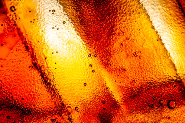 黑色可乐背景下的冰块特写。夏日清凉甜饮的质感，玻璃壁上有泡沫和宏观气泡。嘶嘶作响或浮上水面。图片下载