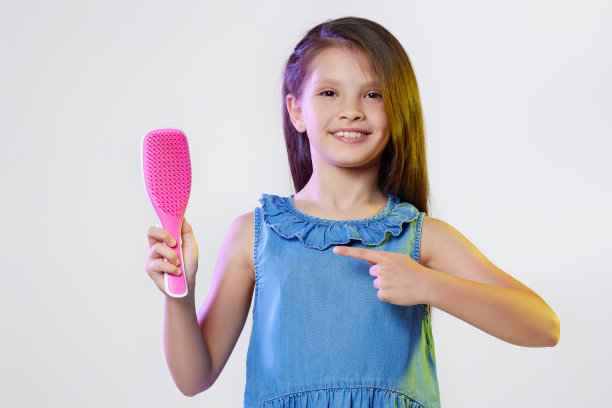 可爱的小女孩拿着梳子在白色的背景下图片下载