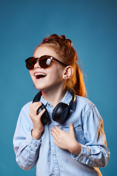 戴着太阳镜和无线耳机的红发小女孩图片下载