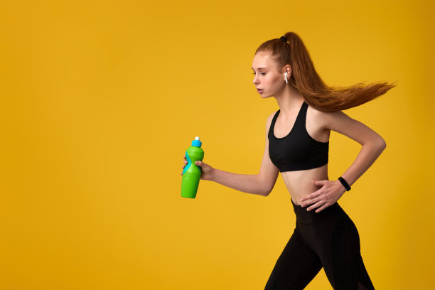 一个年轻的女人手里拿着一瓶水在跑图片下载