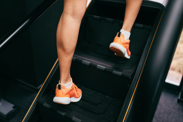 在楼梯踏步机上做腿部运动的女人，在健身房。选择裁剪的照片，适合的女人。特写镜头。图片下载