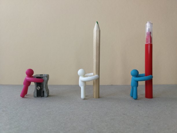 玩具小雕像拿着学校或办公用品，用马克笔、卷笔刀和铅笔，形成一条线，好像从后面看一样图片下载