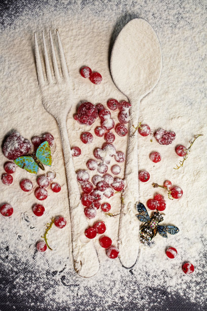 勺子和叉子，红色浆果撒上面粉，顶部放着昆虫形状的小册子。创造性的准备食物。图片下载