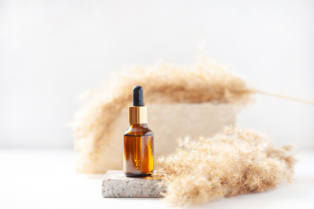 化妆瓶放在石灰华石基座和潘帕斯草上。最小模型的背景。图片下载