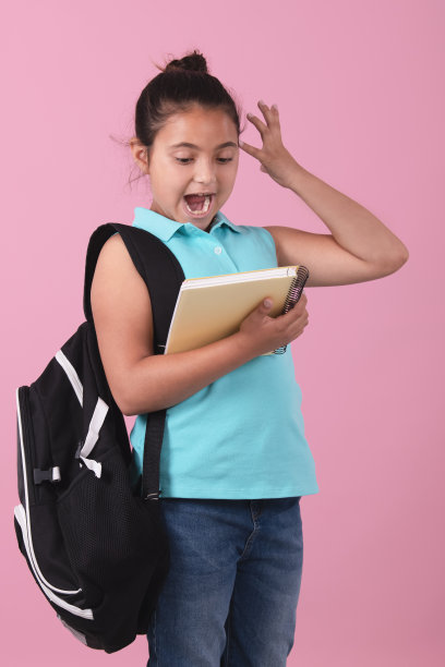 一名女学生拿着笔记本看着笔记本，脸上露出惊讶的表情。图片下载