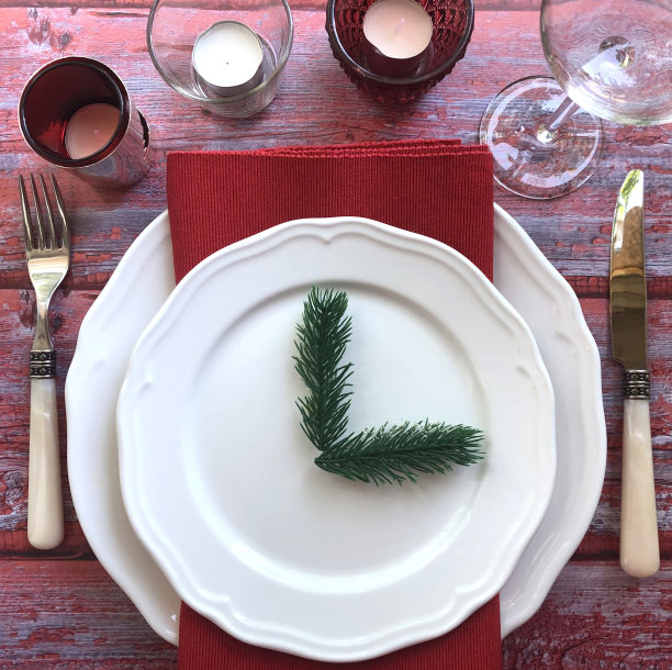 圣诞餐桌布置。蜡烛，酒杯，餐具，餐巾布，盘子。图片下载