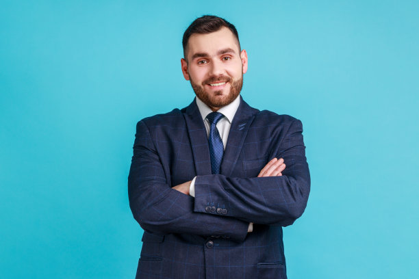 自信的年轻商务男士身穿正装，面带微笑看向镜头，双手交叉图片下载
