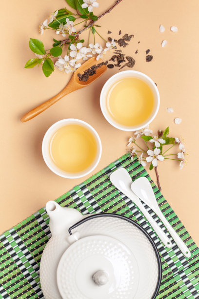 春天的茶道。花草茶在杯子，茶壶和开花的樱桃枝。前视图。平躺图片下载