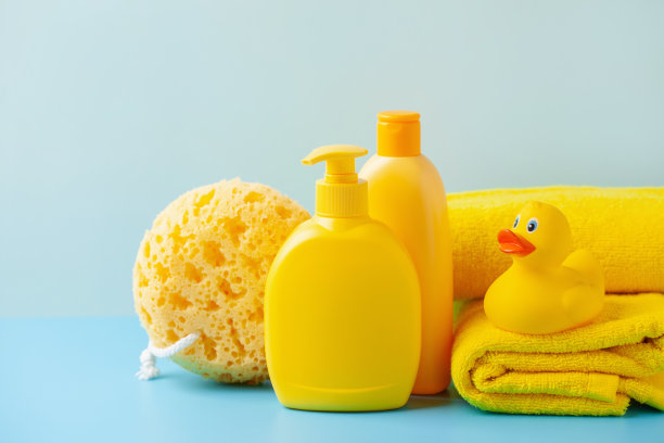 蓝色背景上的婴儿洗发水或肥皂，橡胶黄色的鸭子和毛巾。浴室配件图片下载