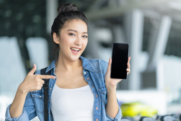 聪明迷人的亚洲女性手持智能手机在应用程序屏幕上查看出租车时刻表智慧城市旅游理念，亚洲女性使用智能手机在终端平台站呼叫出租车图片下载