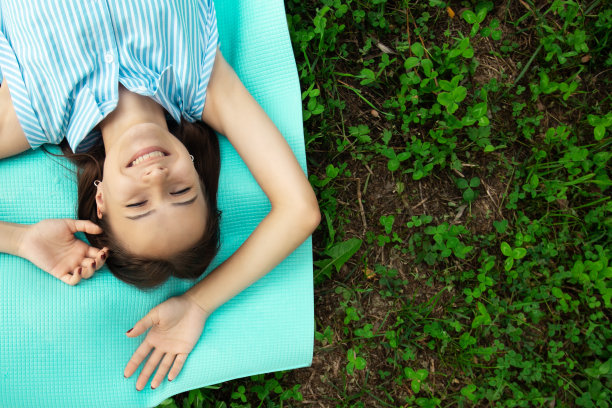 护肤霜，少女微笑，年轻快乐的女人躺在草地上阳光灿烂的日子，年轻快乐的女人在公园度假与复制空间图片下载