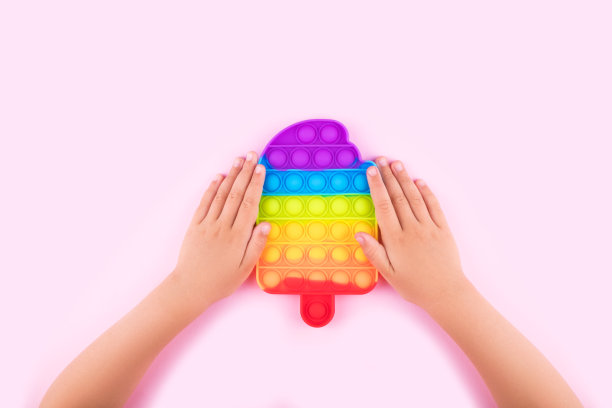 小孩手里拿着彩虹pop它的抗压力玩具。图片下载
