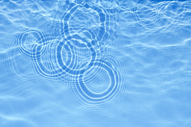浅蓝透明的游泳池水面纹理与水面上的圆圈。时尚抽象的自然背景。水波在阳光横幅与复制空间图片下载