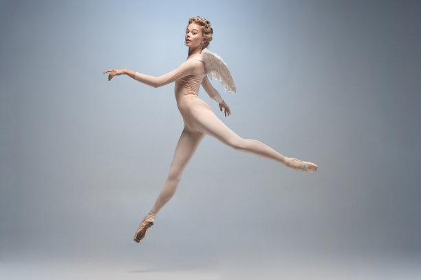 年轻而优雅的芭蕾舞者，芭蕾舞者在白灰色的演播室背景下孤立地跳舞。艺术，运动，行动，灵活性，灵感概念。图片下载