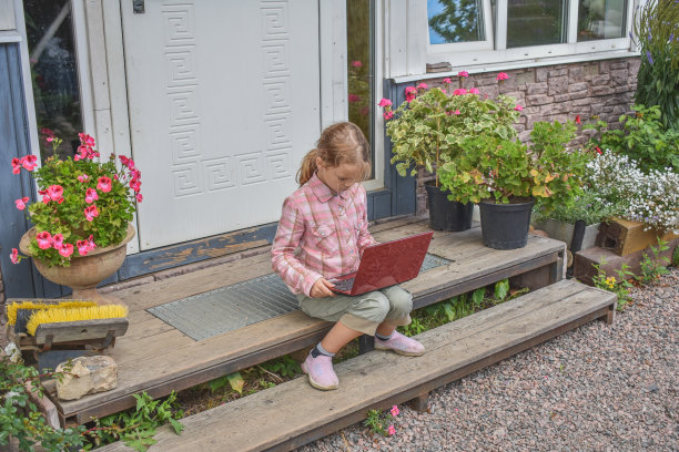 一个女孩带着笔记本电脑坐在房子的门廊上上课，在没有滤镜的远程照片上图片下载