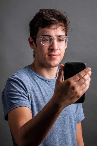 一个年轻人正在看他智能手机的摄像头图片下载