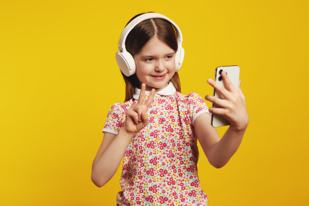 孩子用智能手机用白色耳机听音乐，表现出平和的姿态图片下载