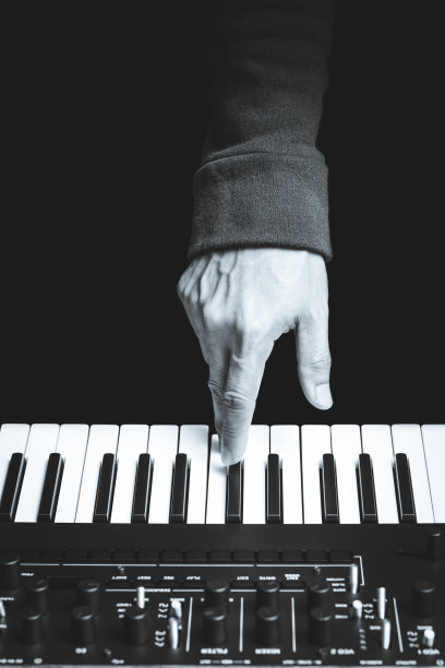 靠近男性音乐家的手指按在合成器键盘上的按键。黑色和白色。孤立在黑色。背景音乐图片下载