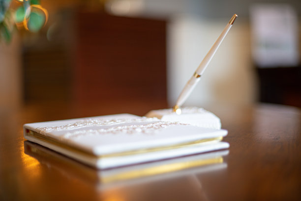 白色的签字笔在白色的笔站在闪亮的木桌附近的签字簿图片下载