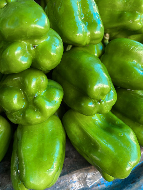 全帧图像的农产品市场堆放新鲜的绿色甜椒(辣椒年)在一个户外果蔬市场出售，聚焦前景图片下载
