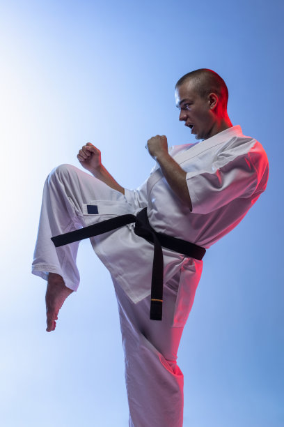 一个白人运动员站在一个战斗姿势孤立在梯度白蓝色的背景。空手道，柔道，跆拳道运动图片下载