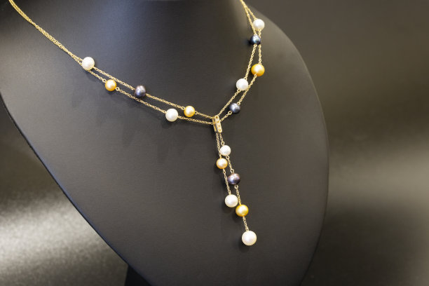 女士的金项链，由链子和珍珠做成，放在黑色的架子上。特写镜头图片下载