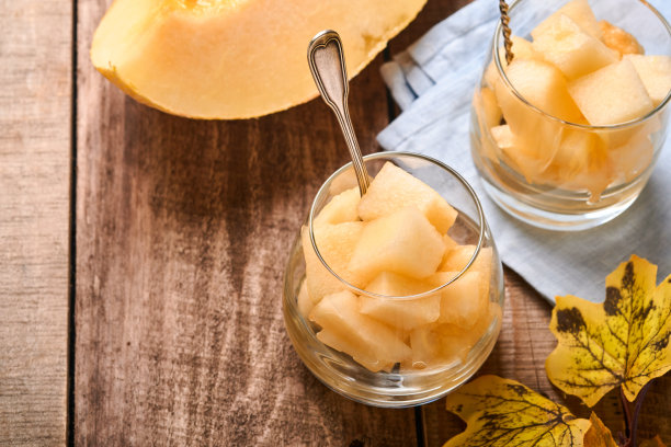 瓜。在一个古老的木制背景上，用玻璃制作水果甜点的新鲜甜瓜片。模拟。前视图。图片下载