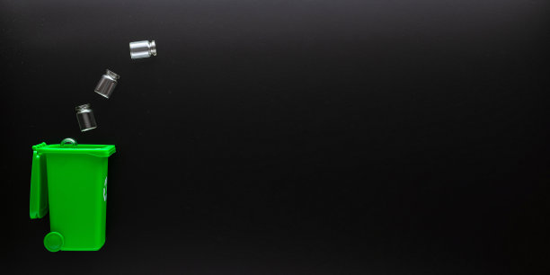 玻璃回收垃圾。垃圾箱容器用于处理垃圾废物，节约环境。黑色背景上的绿色玻璃回收垃圾桶。前视图。图片下载